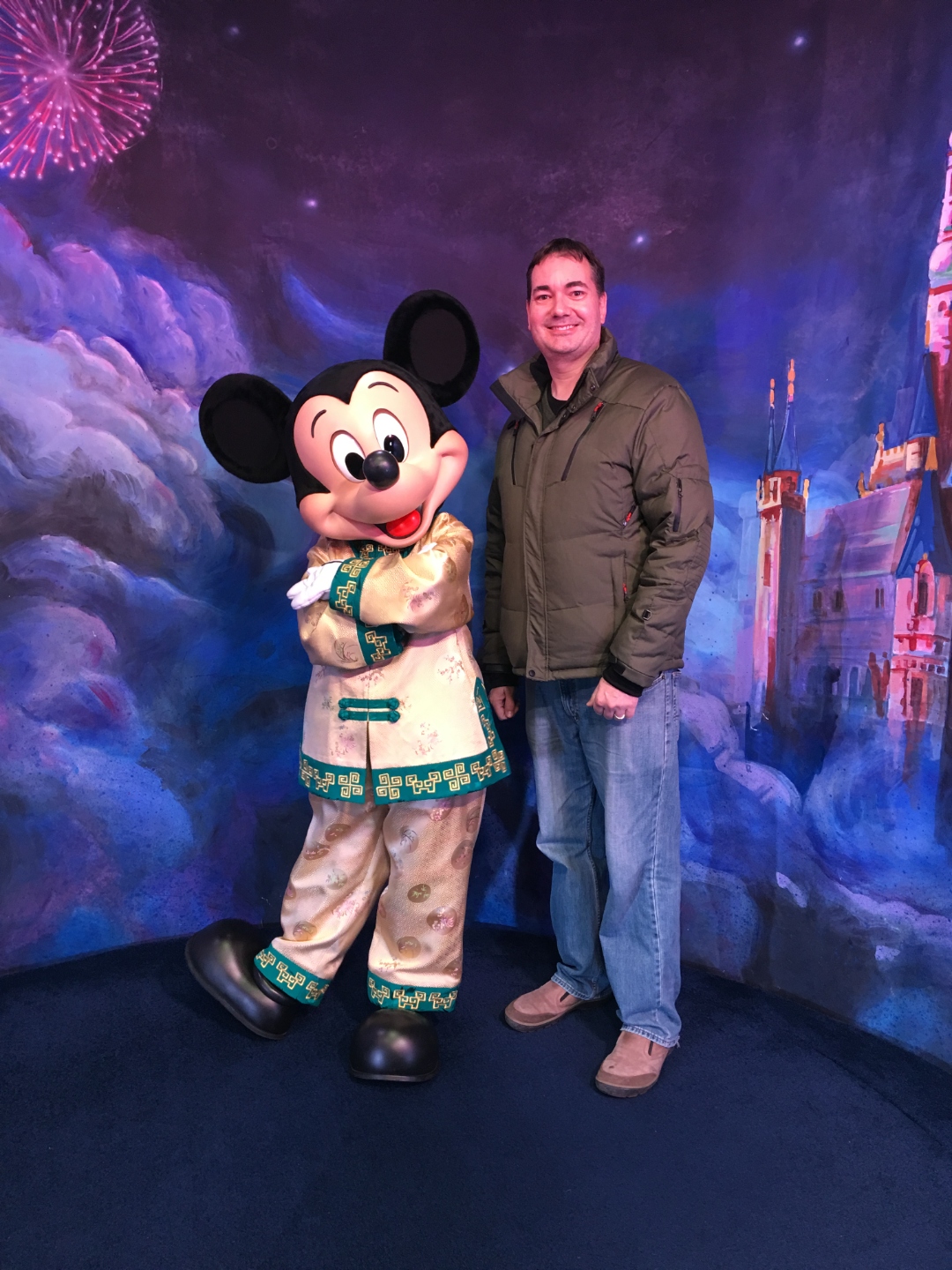 Raymond posing with Mickey Mouse dressed in an embroidered satin outfit at a Disney parks meet and greet.