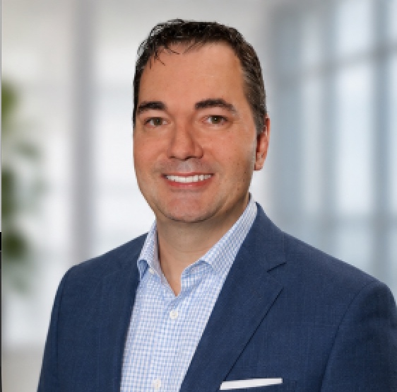 Raymond Conners, Managing Director and Managing Broker at The Agency Bainbridge Island, in a navy blazer and blue checked shirt
